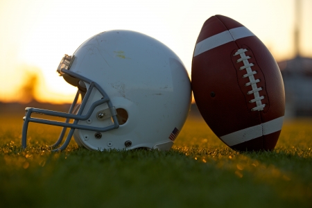 American Football and Helmet on the Field Backlit at Sunsetの写真素材