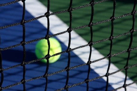 Tennis Court Net close up with the ball and court in backgroundの写真素材