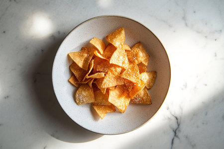 Golden Potato Chips on Pristine Plate with Clean and Inviting White Backgroundの写真素材