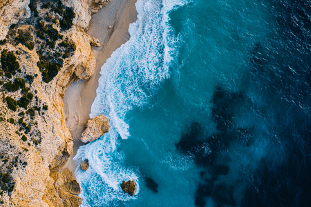 Waves Crashing on an Exotic Beach with Splashes of White Foam Against a Blue Seaの写真素材