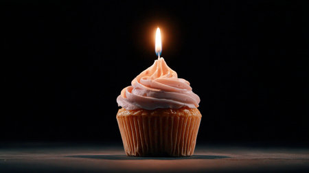 Single birthday cupcake with lit candle on dark backgroundの写真素材