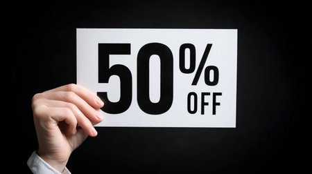 Female hand holding a card with 50 percent off on a black background