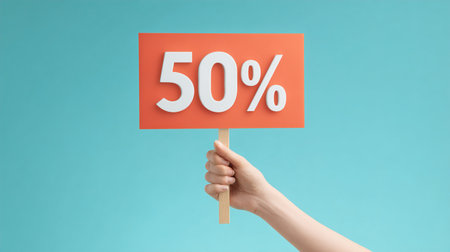 Female hand holding a 50 percent discount sign on a blue background.の写真素材