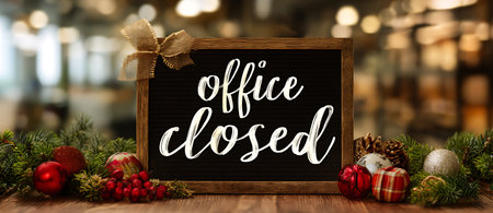A framed blackboard with "office closed" written in white script is decorated with a burlap bow on the top left. It is placed on a wooden surface and surrounded by Christmas elements like red berries, pine cones, red, silver, and plaid ornaments, and fir branches. The background is a blurred bokeh of warm lights.の写真素材