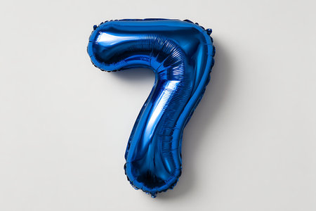 A shiny blue metallic foil balloon representing the number seven is presented against a neutral gray...