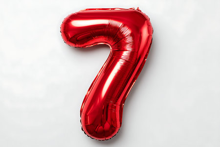 A single, shiny red foil balloon shaped like the number seven is presented against a clean white...