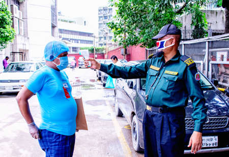 Coronavirus epidemic. Dhaka, Bangladesh - July 09 2020: Security personnel checking temperature before entering the Safety Area. Security procedures.のeditorial素材