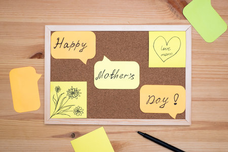 On a wooden background cork Board with stickers with the inscription happy mother's day.