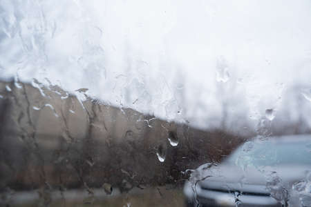 view from the car window with dripping raindrops and a blurry view.の写真素材