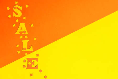 paper background divided diagonally by yellow and orange colors on which the word SALE.の写真素材