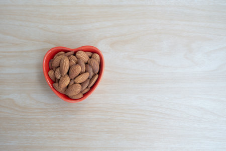 Almonds and nutcrackers, almond nuts peeled and roasted in a red ceramic bowl, top view with copy space.の写真素材