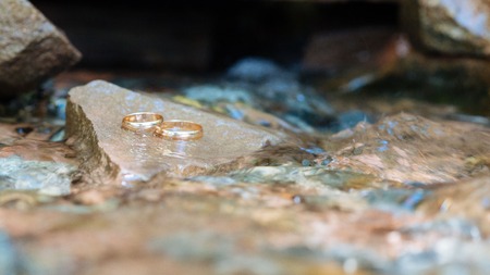 Wedding rings on the heart shaped rock under clear waterの写真素材