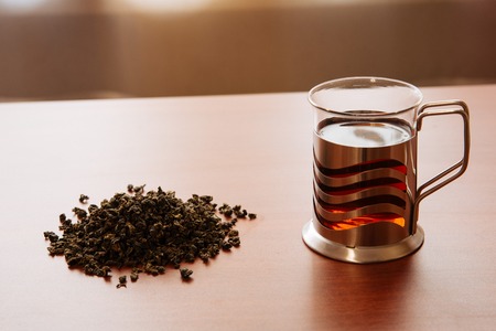 glass mug and poured tea on wooden tableの写真素材