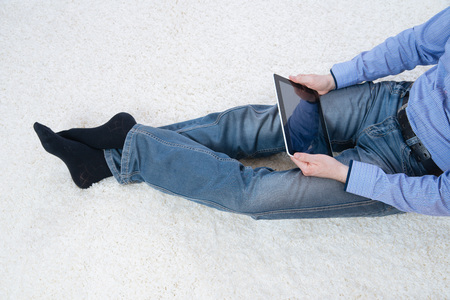 young man sitting on a white carpet with tabletの写真素材