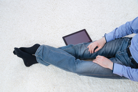 young man sitting on a white carpet with tabletの写真素材