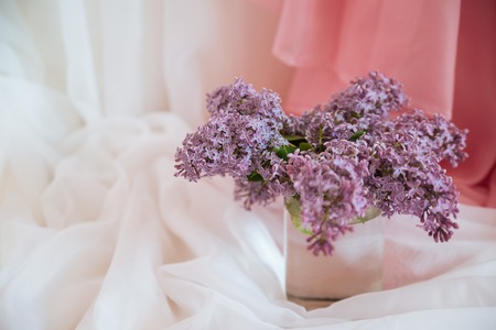 Purple lilac flowers in glass jar against white textile backgroundの写真素材