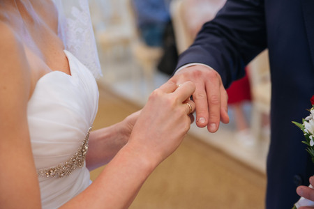 The bride wears a wedding ring on the groom. Closeup photoの写真素材