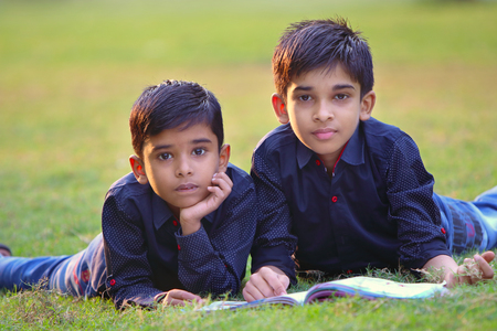 Indian cute brother studying together in green parkの写真素材