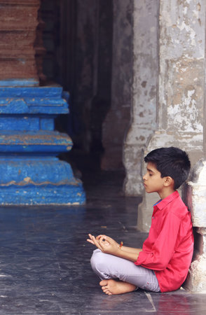 Indian young boy meditating at hindu temple