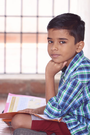 Portrait of Indian Little Boy Posing to Camera with Textbook