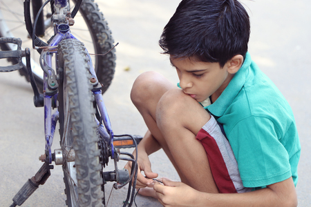 Indian Little Boy repairing cycleの写真素材