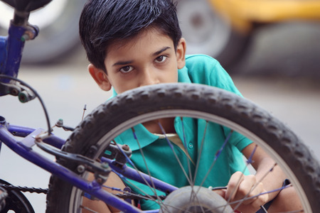 Indian Little Boy repairing cycleの写真素材