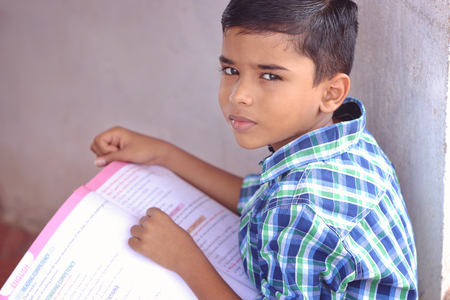 Portrait of Indian Little Boy Posing to Camera with Textbookの写真素材
