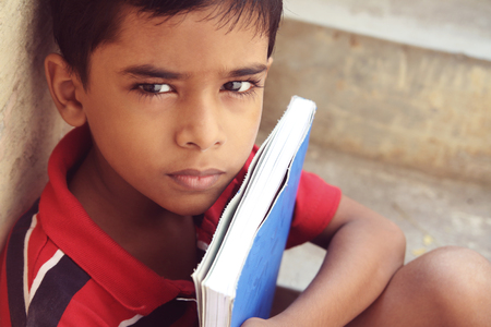 Portrait of Indian Little Boy Posing to Camera with Textbookの写真素材