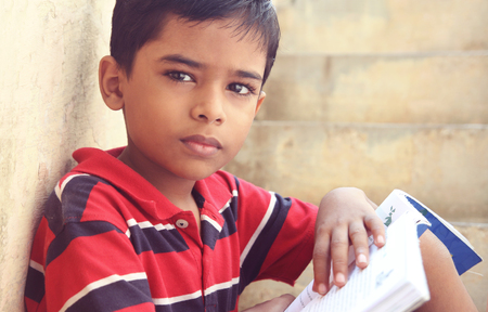 Portrait of Indian Little Boy Posing to Camera with Textbookの写真素材