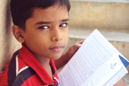 Portrait of Indian Little Boy Posing to Camera with Textbookの写真素材