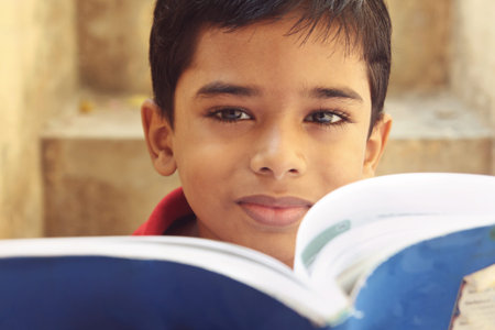 Portrait of Indian Little Boy Posing to Camera with Textbook