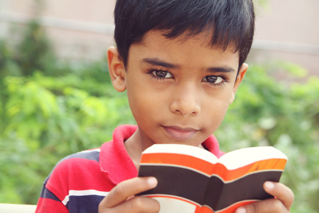 Portrait of Indian Little Boy Posing to Camera with Textbookの写真素材