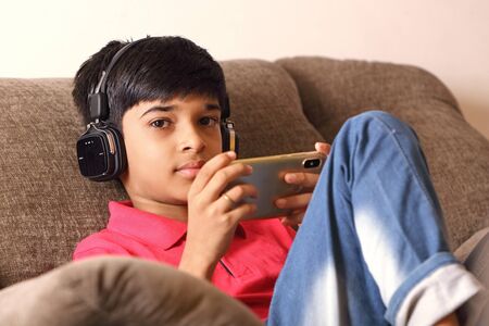 Indian young boy listen music with headphone and holding mobilephoneの写真素材