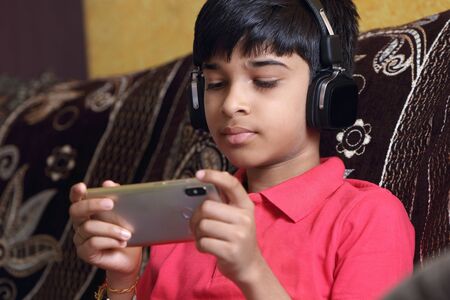 Indian young boy listen music with headphone and holding mobilephone