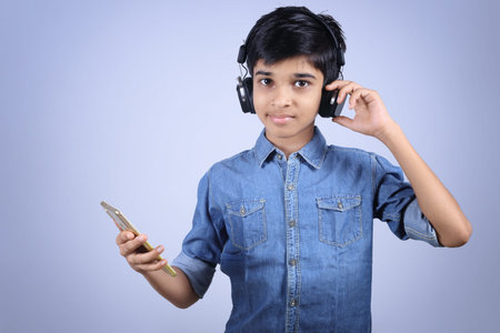 Indian young boy listen music with headphone and holding mobilephone