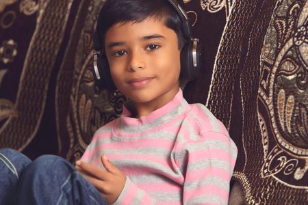 Indian young boy listen music with headphone