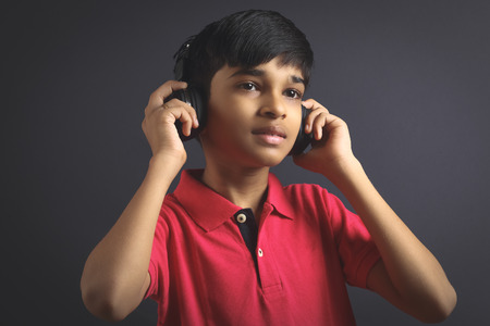 Indian young boy listen music with headphoneの写真素材