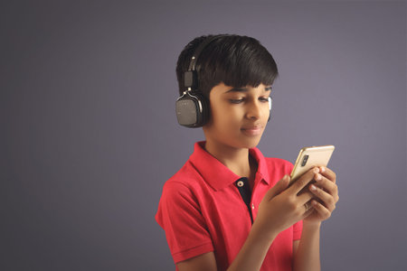 Indian young boy listen music with headphone and holding mobilephone