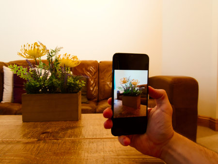 Man shooting a photo of a bed of flowers on phone.