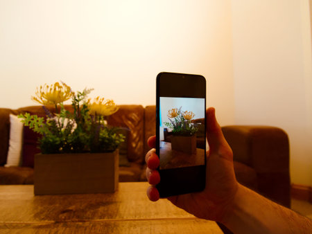 Man shooting a photo of a bed of flowers on phone.