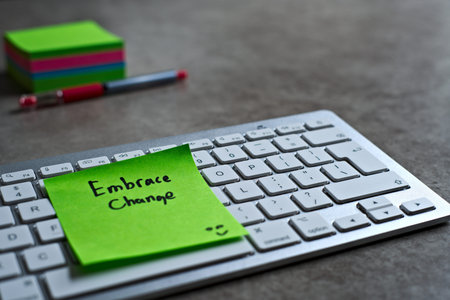 Embrace Change green sticky note left on keyboard. The bright note stands out against the keys,...