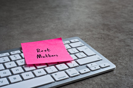 Rest Matters sticky note left on keyboard. The bright note stands out against the keys, symbolising...