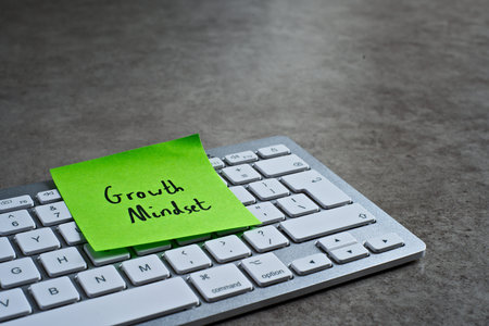 Growth Mindset sticky note left on keyboard. The bright note stands out against the keys,...
