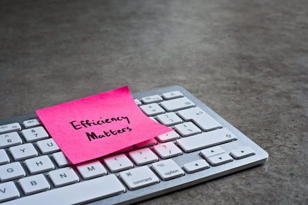 Efficiency Matters sticky note left on keyboard. The bright note stands out against the keys,...