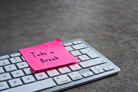 Take a Break sticky note left on keyboard. The bright note stands out against the keys, symbolising...