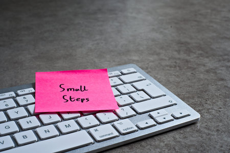 Small Steps sticky note left on keyboard. The bright note stands out against the keys, symbolising...