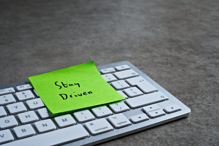 Stay Driven sticky note left on keyboard. The bright note stands out against the keys, symbolising...