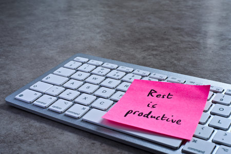 Rest is productive sticky note left on keyboard. The bright note stands out against the keys,...