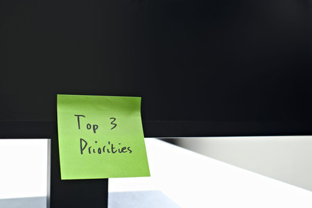 Top 3 Priorities sticky note left on a monitor. The bright note stands out against the monitor,...