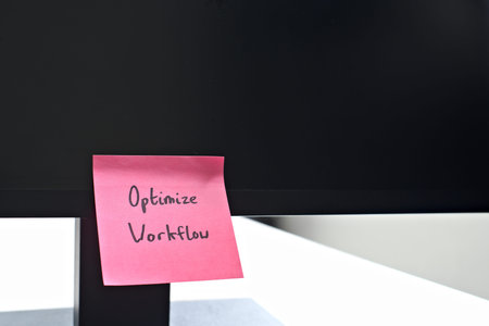 Optimize Workflow sticky note left on a monitor. The bright note stands out against the monitor,...